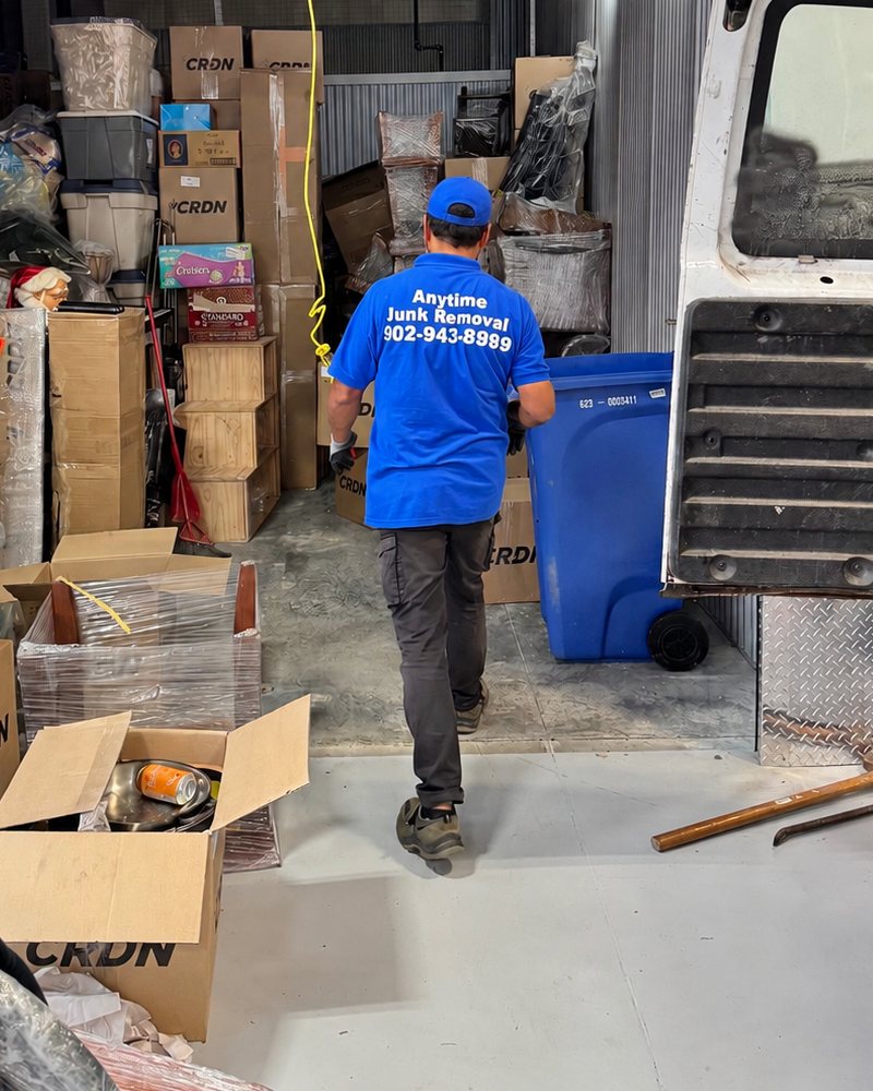 Anytime Junk Removal crew member carrying boxes out of a packed storage unit in Halifax